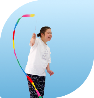 A sensory and creative dancer is dancing with a rainbow ribbon with a huge smile on her face