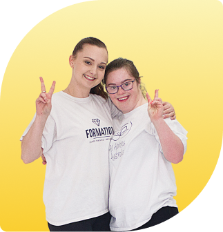 one of our friends from Formation dance and a All Abilities Australia dancer are hugging and holding the peace sign with big smiles on their face